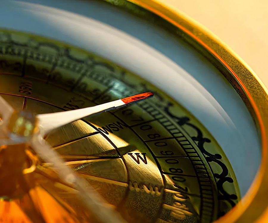 Close-up of a brass compass needle pointing west
